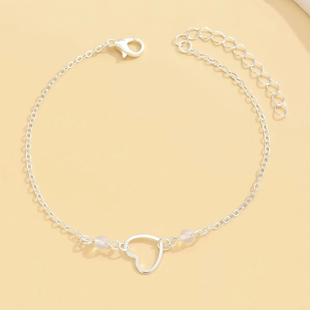 Gold and silver adjustable women's ankle bracelets with a small heart pendant on a chain.