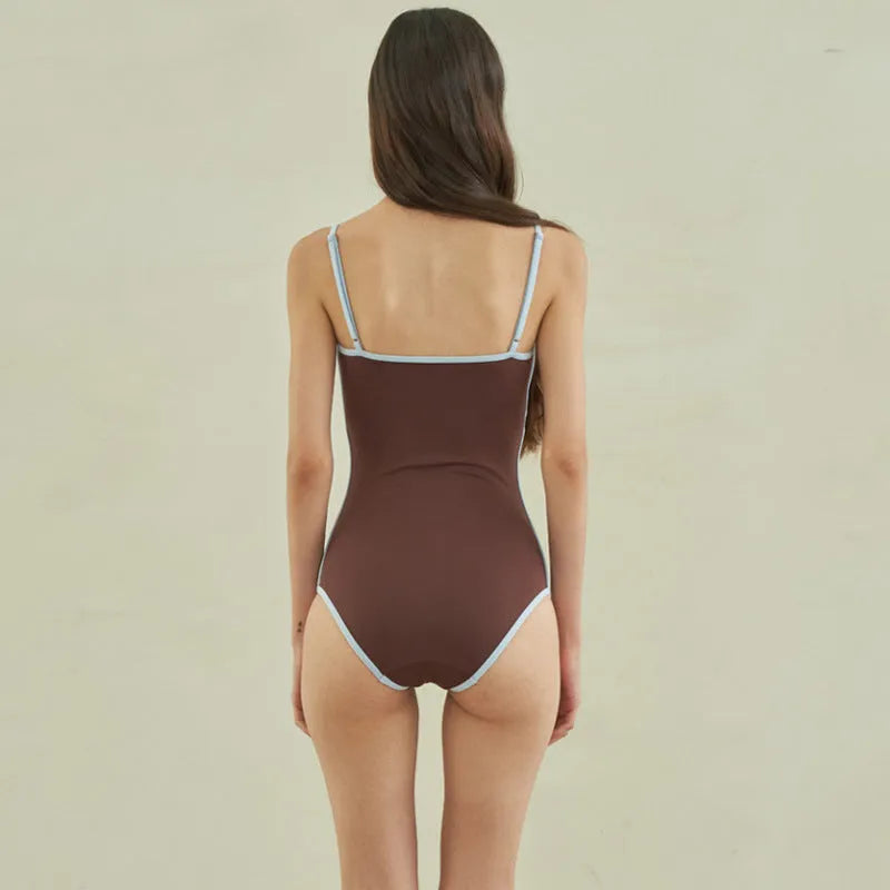 Brown women's one-piece swimsuit with triangle front and adjustable tie-back straps on a neutral background.