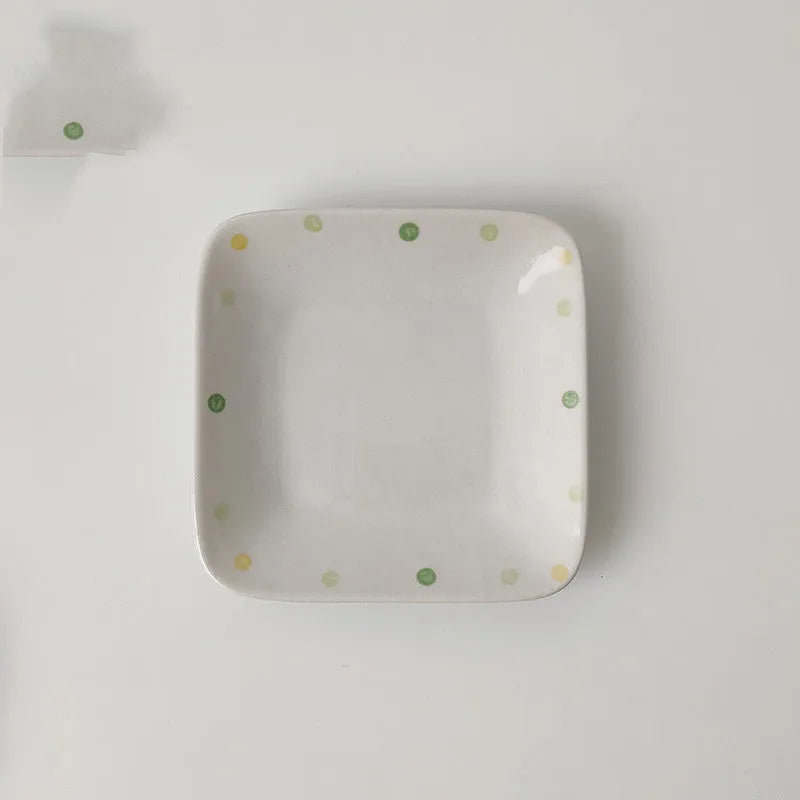 Japanese-style dot pattern porcelain plates and bowls in irregular oval and round shapes on a table.