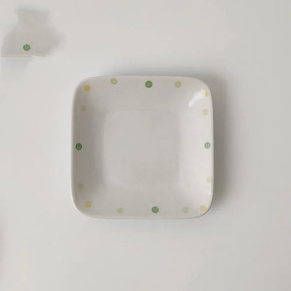 Japanese-style dot pattern porcelain plates and bowls in irregular oval and round shapes on a table.
