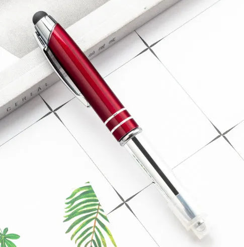 Red metal multifunctional stylus ballpoint pen with LED light on a desk.