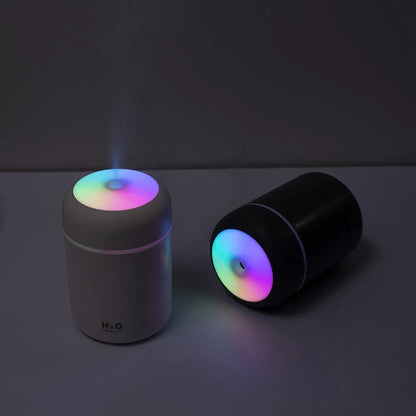 Pink USB desktop humidifier with LED lights and water tank on wooden desk