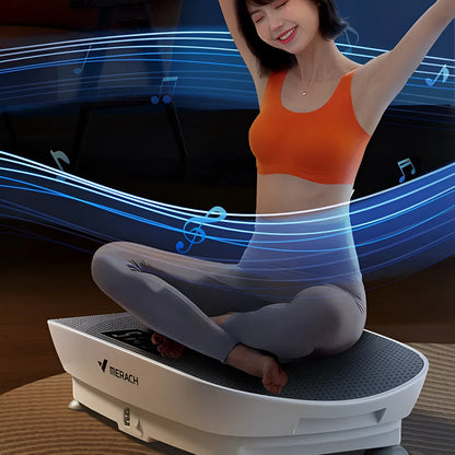 Grey portable vibration plate on a wooden floor, showing its slim 16cm profile and textured platform surface.