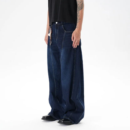 Dark blue distressed wide leg Machete jeans laid flat, showing washed denim texture.