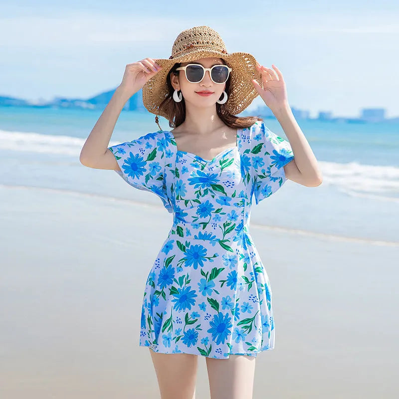 Blue floral print women's dress-style one-piece swimsuit on a hanger
