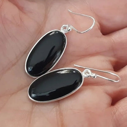 A pair of women's silver-plated alloy earrings with an oval black agate geometric pendant.