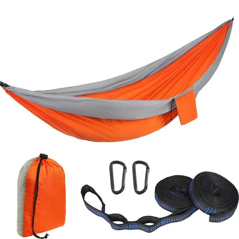 Parachute cloth double camping hammock in chosen colour, with black buckles and round ropes on a tree.