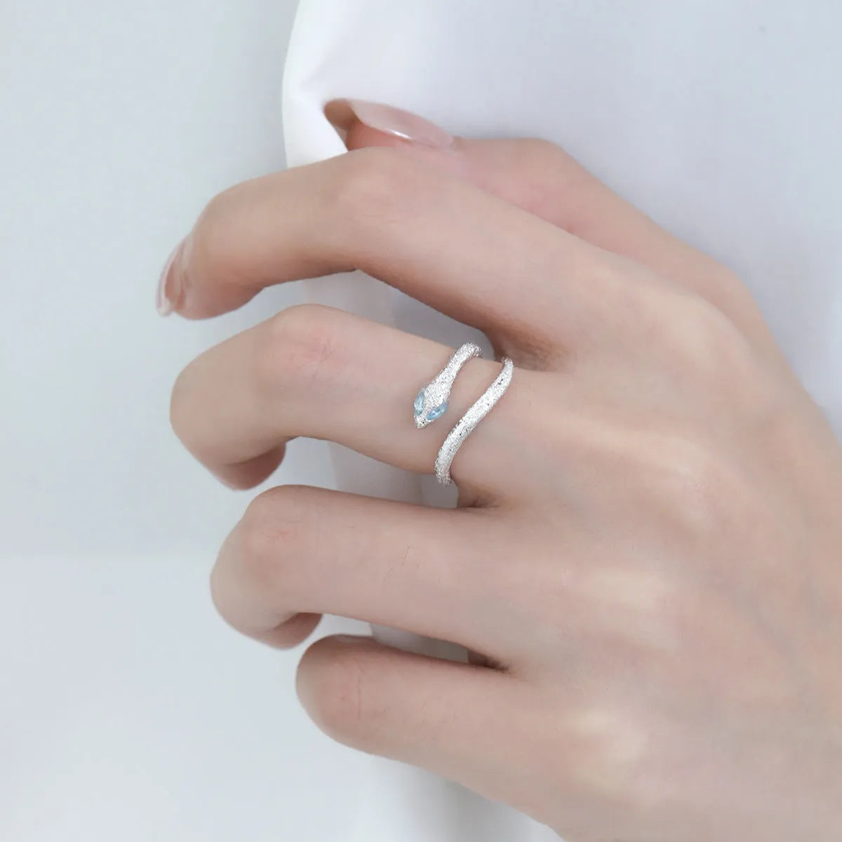 Platinum colour adjustable snake design ring for women on a neutral background.