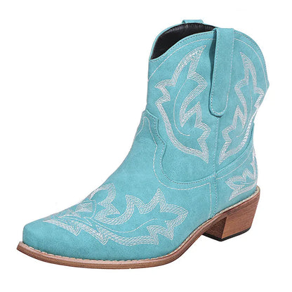 Blue women's cowboy ankle boots with embroidery and a low wedge heel on a wooden floor.