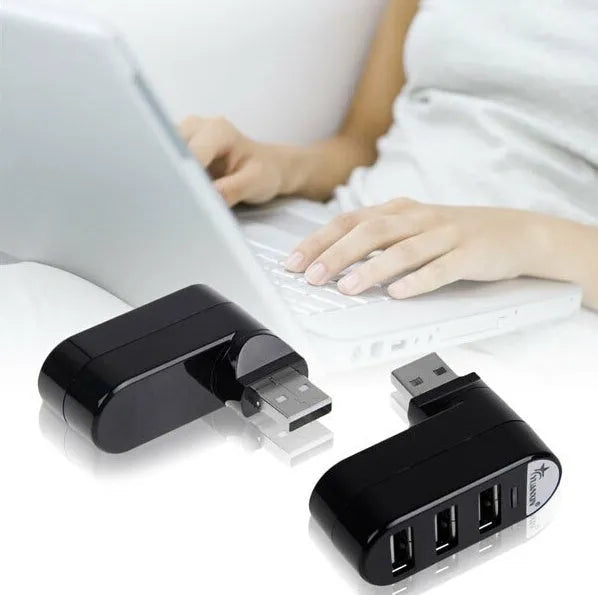 Black and white USB 2.0 hub splitter with spin colour casing on a desk next to a laptop.