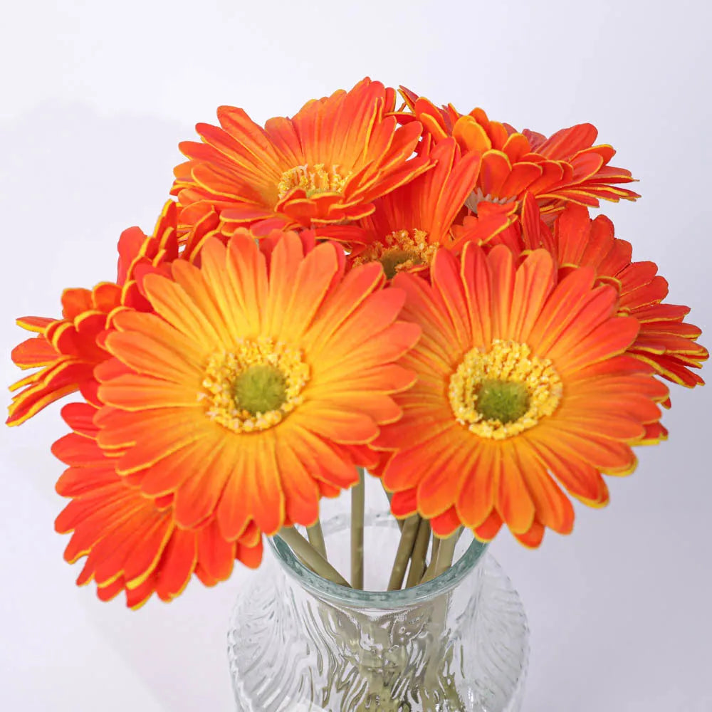 Silk artificial flower bouquet in a white polyurethane pot on a wooden table.