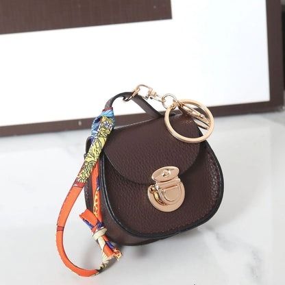 Solid colour PVC coin purse keychain shown in saddle bag black, orange, brown, red, grey, and pink.