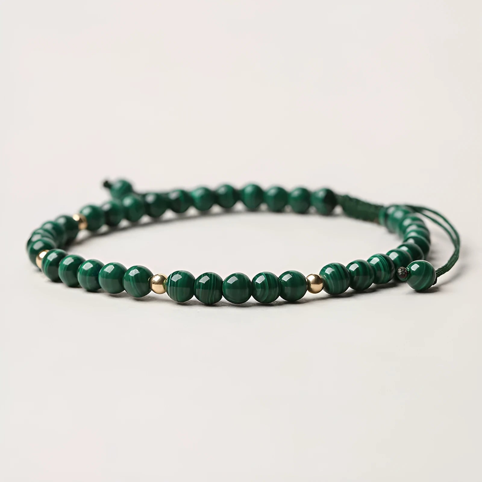 Handwoven green malachite crystal bracelet for women with golden ball accents.