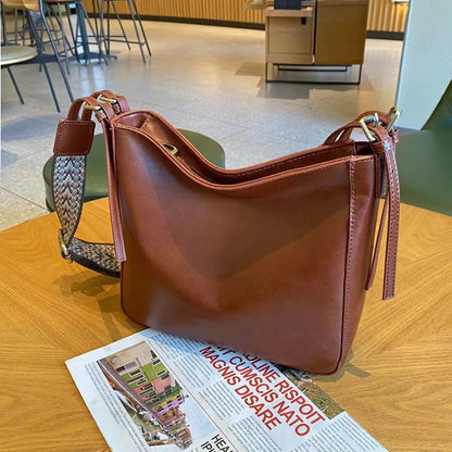 Women's black genuine leather shoulder messenger bag showing structured square shape and single strap.