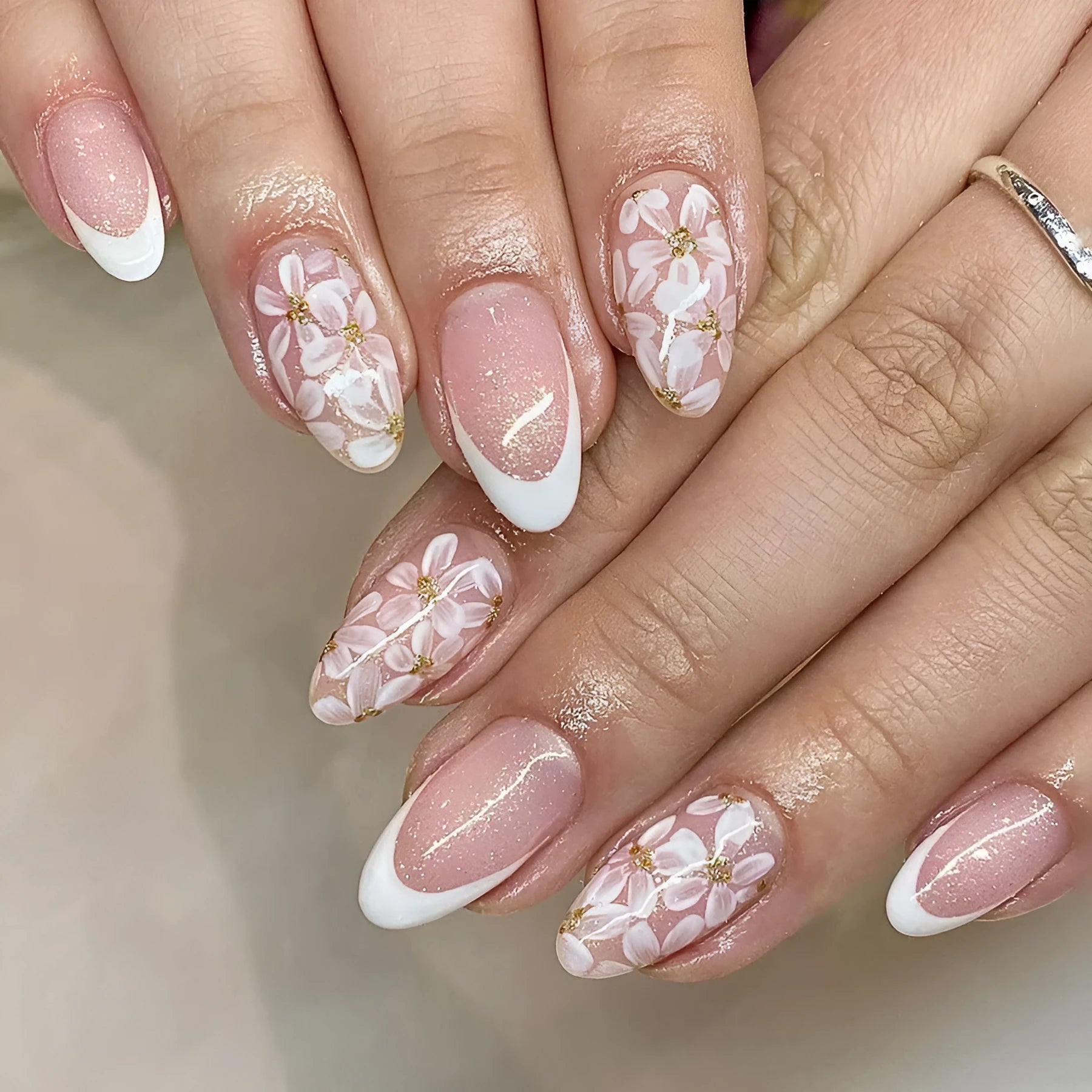 Short glossy almond false nails with glittering powder flower designs in C625 colour