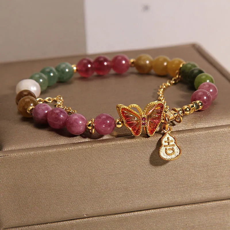 Close-up of a jade green tourmaline butterfly gourd charm on a brown agate bracelet for women.
