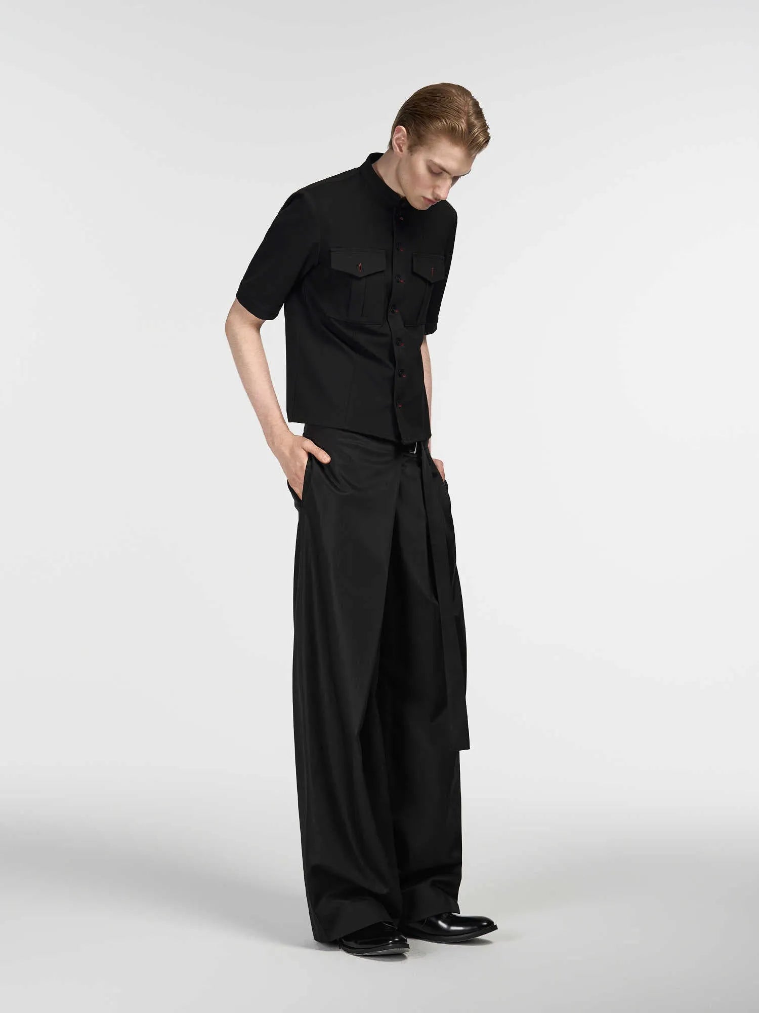 Black straight-leg trousers with single front pleat and adjustable waistband on a hanger