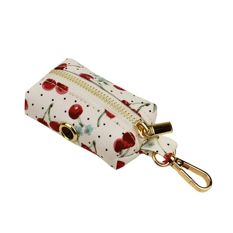 Red cherry printed dog collar with light gold buckle and matching leash, bow, vest and poop bag holder set