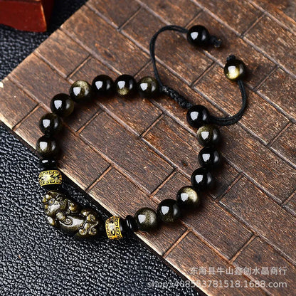 Handmade golden obsidian Pi Xiu bracelet with Chinese zodiac design on wrist.