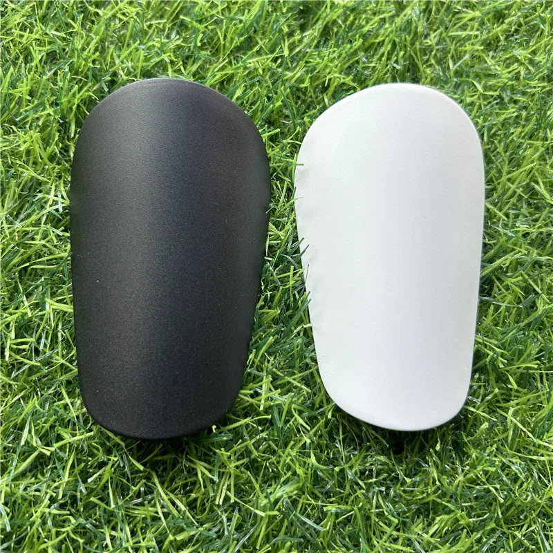 Extra small 8x5cm black and white plastic football shin guards for junior players.