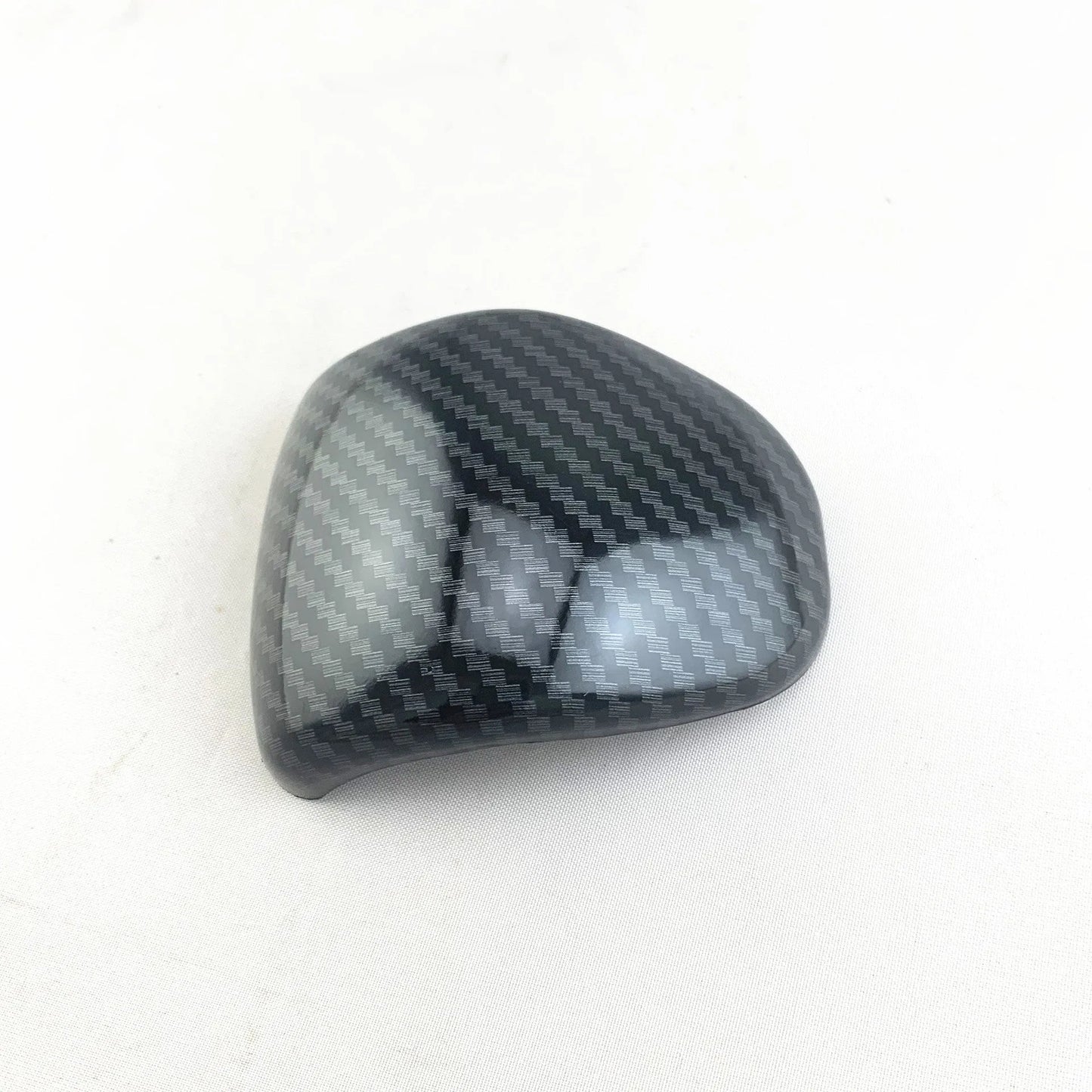 Black carbon fibre effect plastic cover for a car gear shift knob.