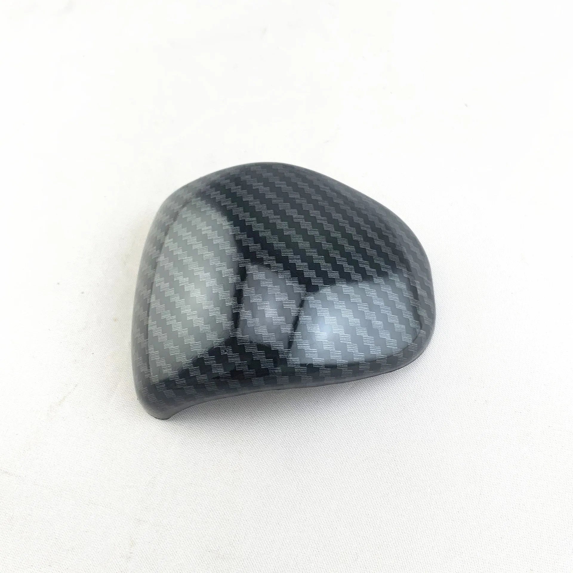Black carbon fibre effect plastic cover for a car gear shift knob.