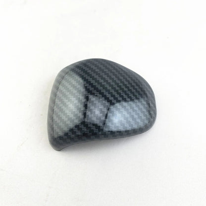 Black carbon fibre effect plastic cover for a car gear shift knob.
