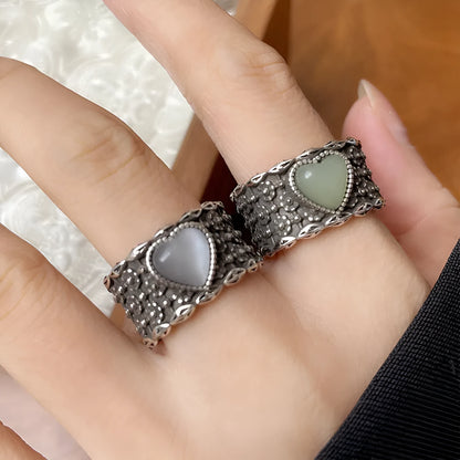 Retro style wide silver heart shape ring with adjustable band on a wooden surface