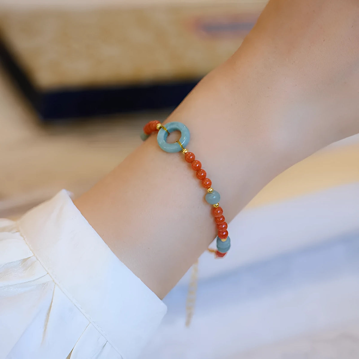 Natural South Red Agate women's bracelet with safety buckle on a wrist, showing geometric beads and auspicious patterns.