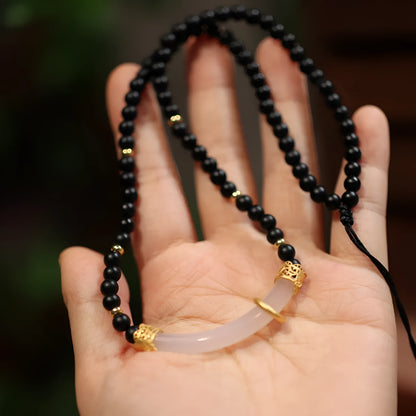 Close-up of a U-shaped necklace with frosted black agate, white chalcedony, and a 925 silver pendant on a beaded chain.
