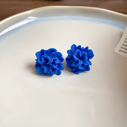 Handmade geometric women's earrings with blue resin flower and cloth material on silver needle setting.