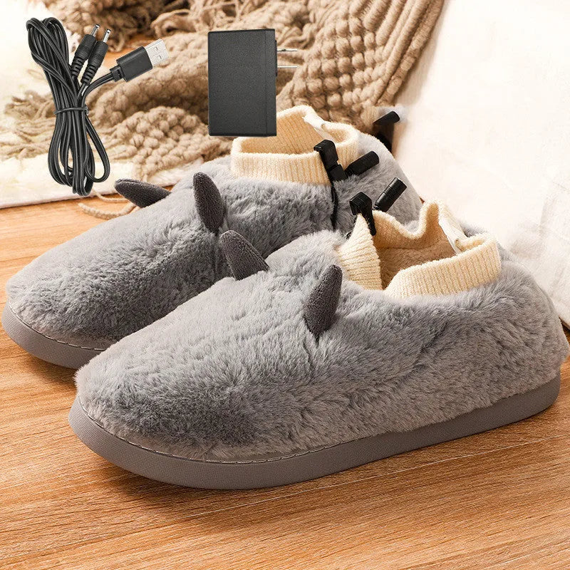 USB heating slippers in black plugged into a laptop, showing the cable and soft velvet upper.