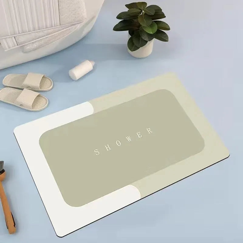 Oval grey bath mat with non-slip rubber bottom on a tiled floor, showing absorbent fabric surface