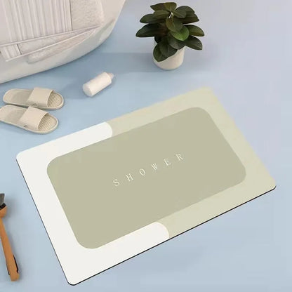 Oval grey bath mat with non-slip rubber bottom on a tiled floor, showing absorbent fabric surface