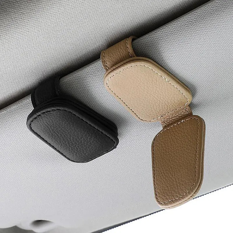 Car sunglasses holder clip with PU leather case attached to a sun visor.