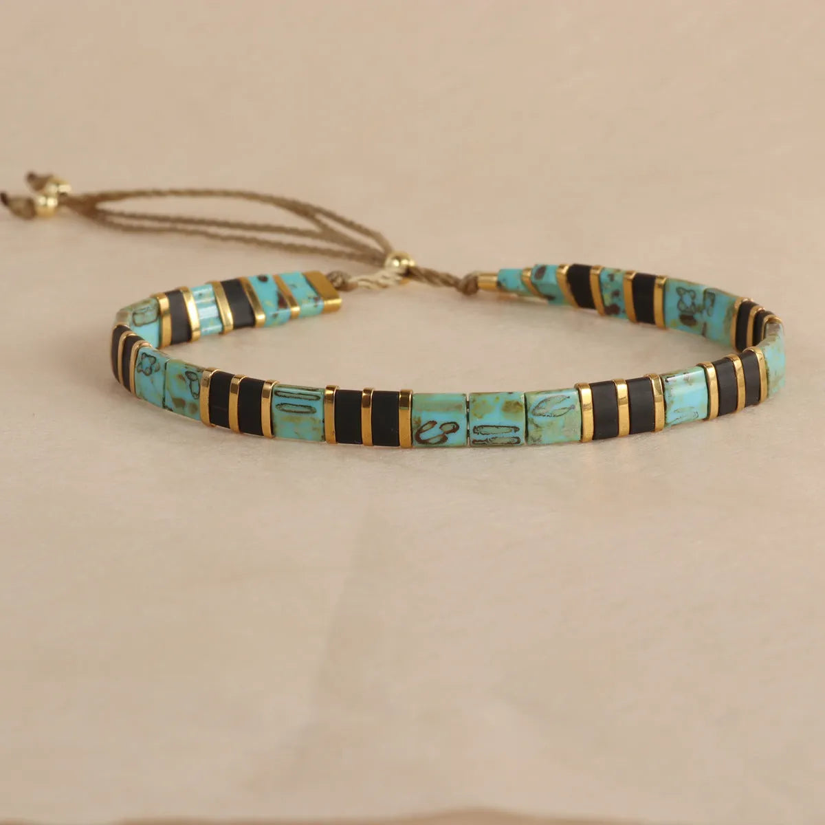 Geometric glass beaded pull bracelet in multiple colours including milky white, black, retro green, light blue, and red