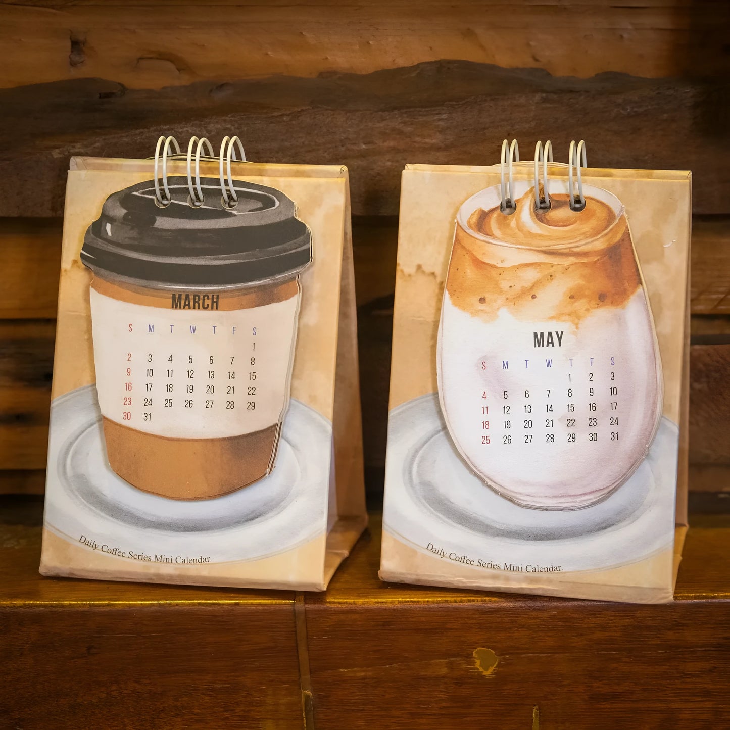 Set of four different themed 2025 mini paper desk calendars on a desk.