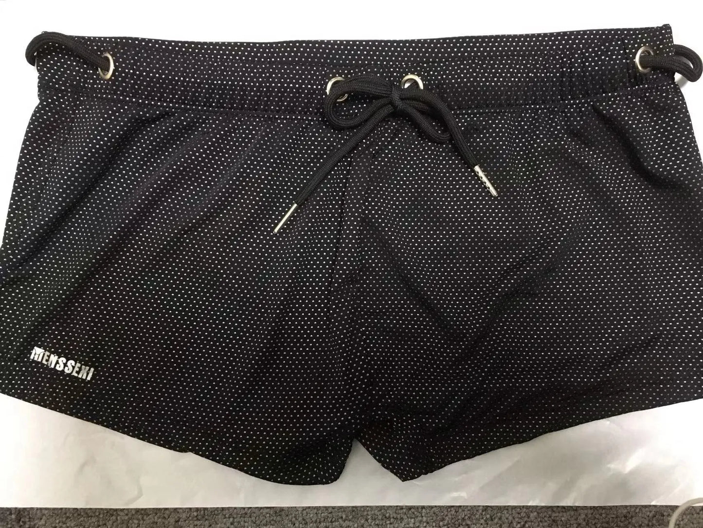 Men's low waist swim trunks in stretch nylon on a man, showing elastic waistband and boxer-style cut.