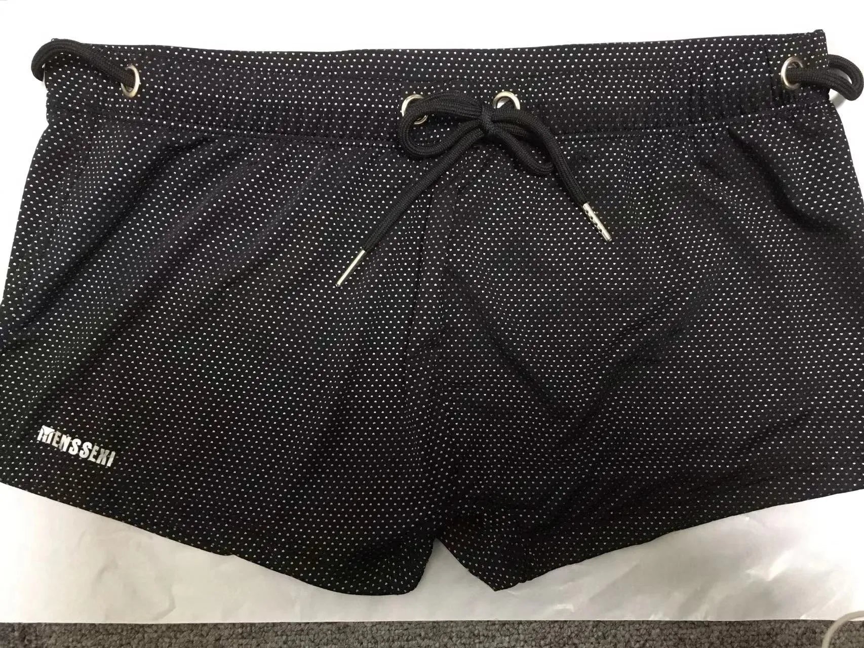 Men's low waist swim trunks in stretch nylon on a man, showing elastic waistband and boxer-style cut.
