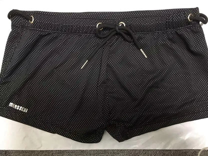 Men's low waist swim trunks in stretch nylon on a man, showing elastic waistband and boxer-style cut.