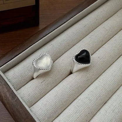 Adjustable sterling silver ring with a heart-shaped black agate stone in a niche setting on a woman's finger.