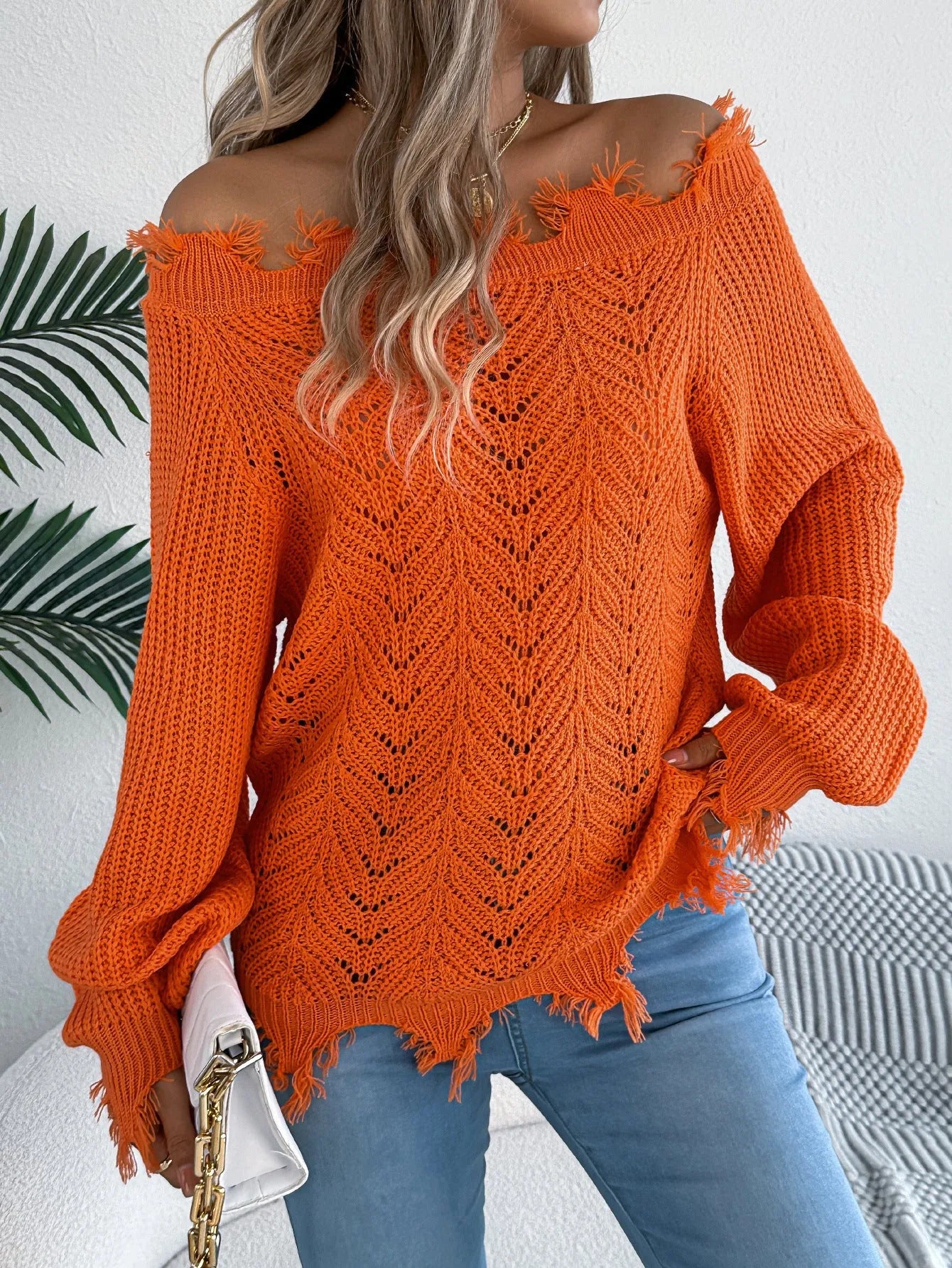 Women's black off-the-shoulder pullover sweater with hollow-out long sleeves on a hanger.