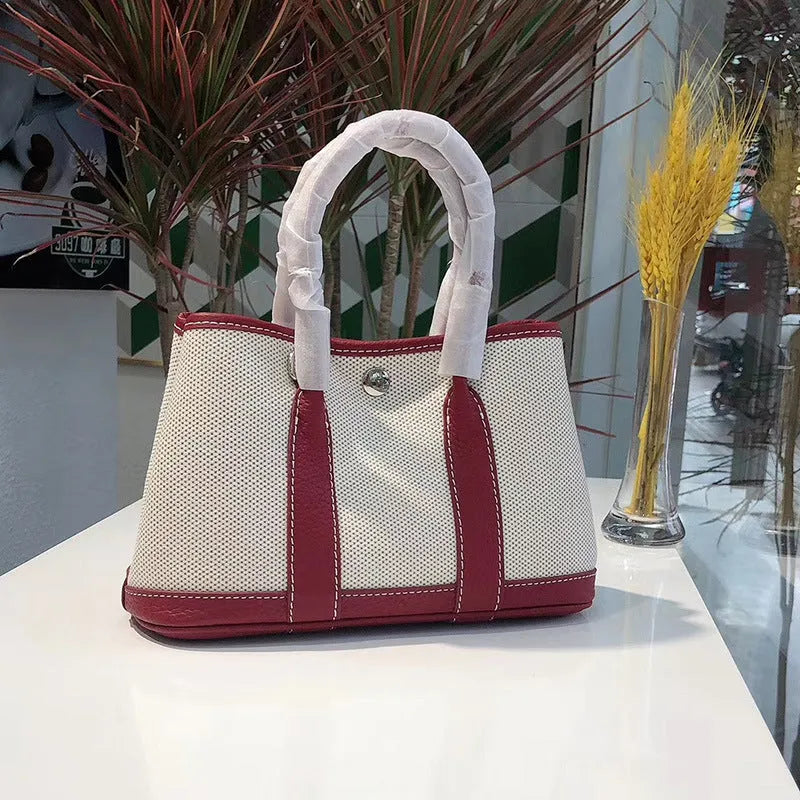Canvas and leather tote bag in bucket shape with crossbody strap, shown in black, brown, gray or red colour options