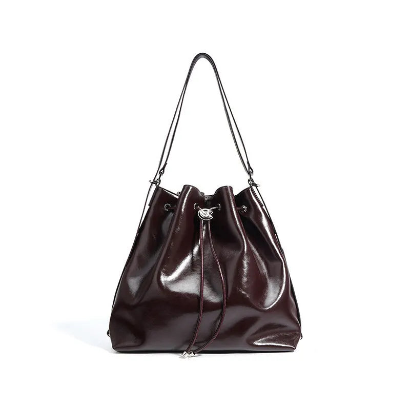 Brown genuine leather retro-style bucket bag with a single shoulder strap showing internal zipped compartments.