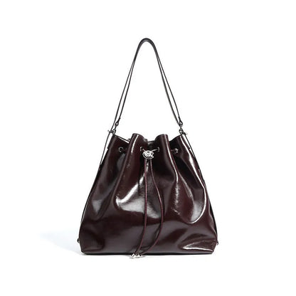 Brown genuine leather retro-style bucket bag with a single shoulder strap showing internal zipped compartments.
