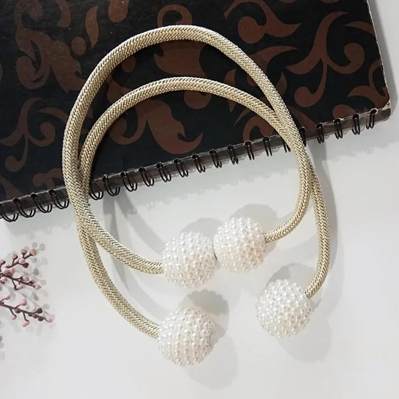 Magnetic curtain tiebacks with white pearl beads and fabric loops holding gathered curtain