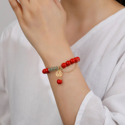 Retro women's bracelet with red cinnabar fu charm, jade bead, and tassel.