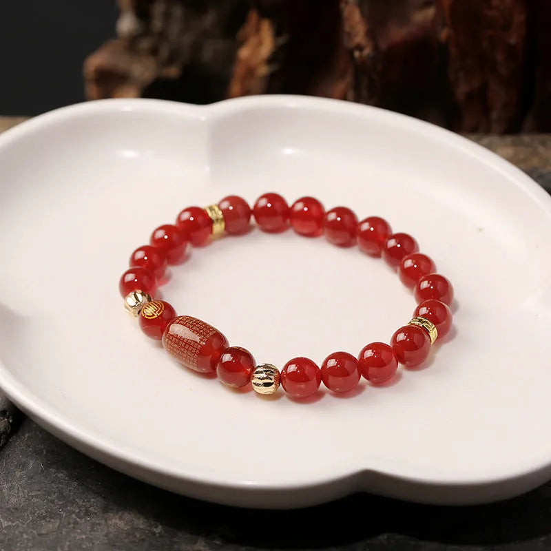 A red agate beaded bracelet with a Guanyin pendant on a white background.