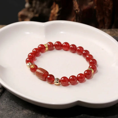 A red agate beaded bracelet with a Guanyin pendant on a white background.