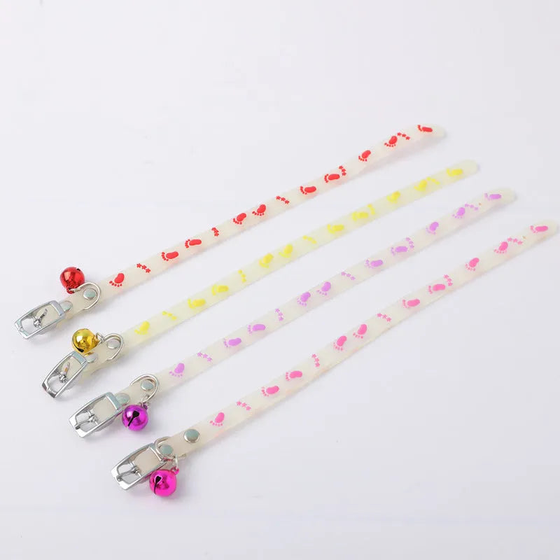 Glowing adjustable luminous collar for cats on a dark background, showing silicone chain and metal bell.